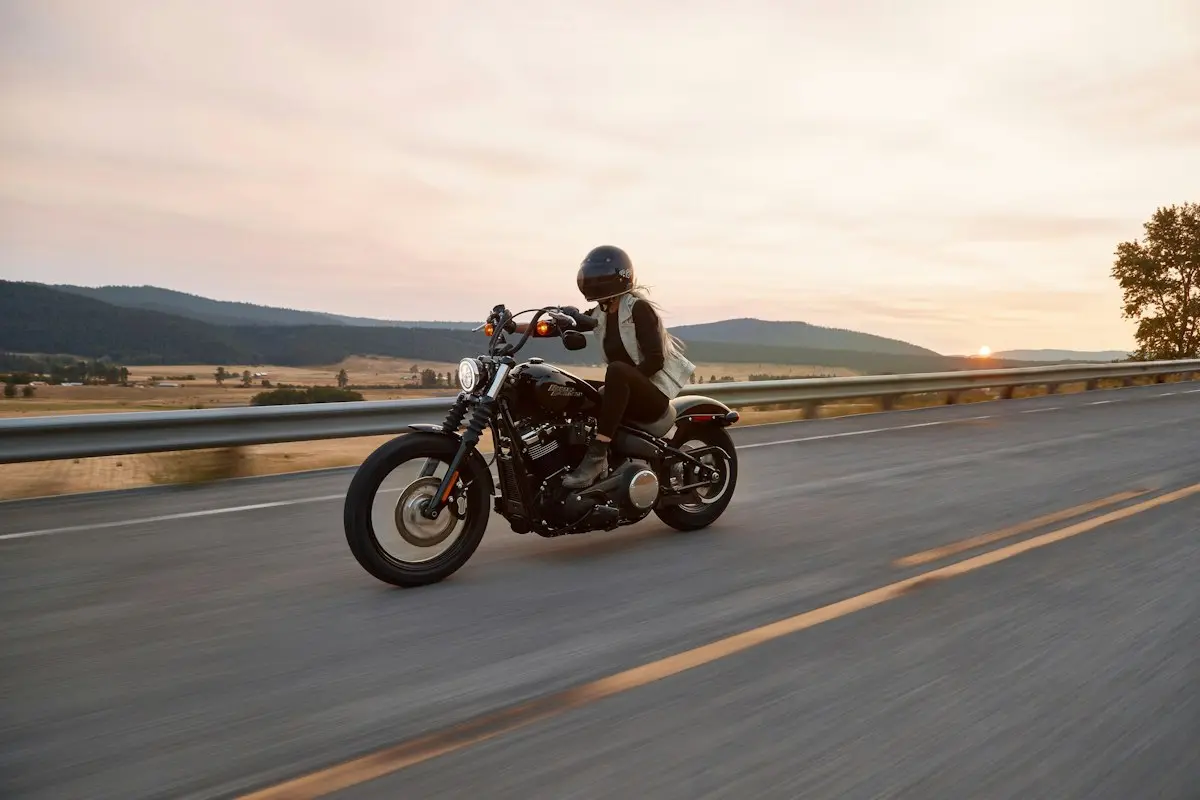 Motociclista con casco en carretera al atardecer