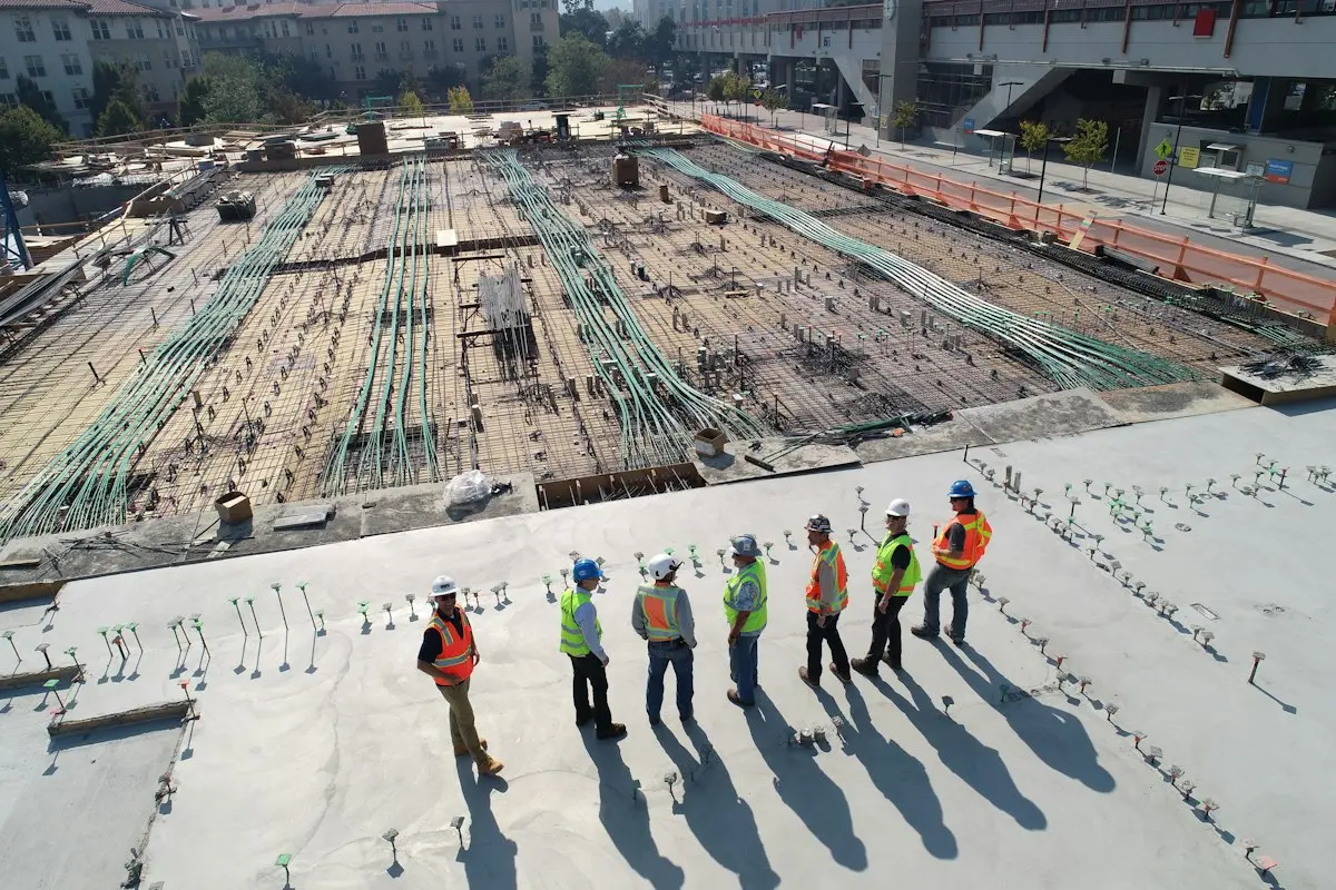 Grupo de obreros con cascos y chalecos en un sitio de construcción